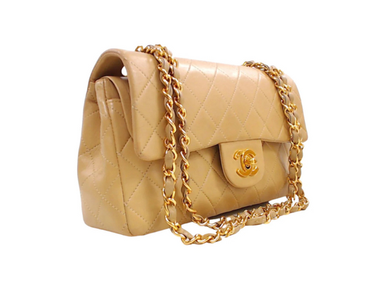 Classic Chanel double flap bag in beige lambskin leather with gold hardware and chain strap.