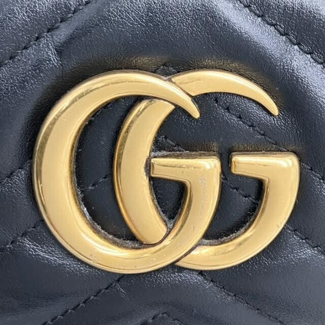 Nærbillede af Gucci GG-logo i antik guld på Marmont Mini crossbody taske
