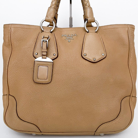 Detaljeret frontvisning af Prada logo og struktur i beige læder.