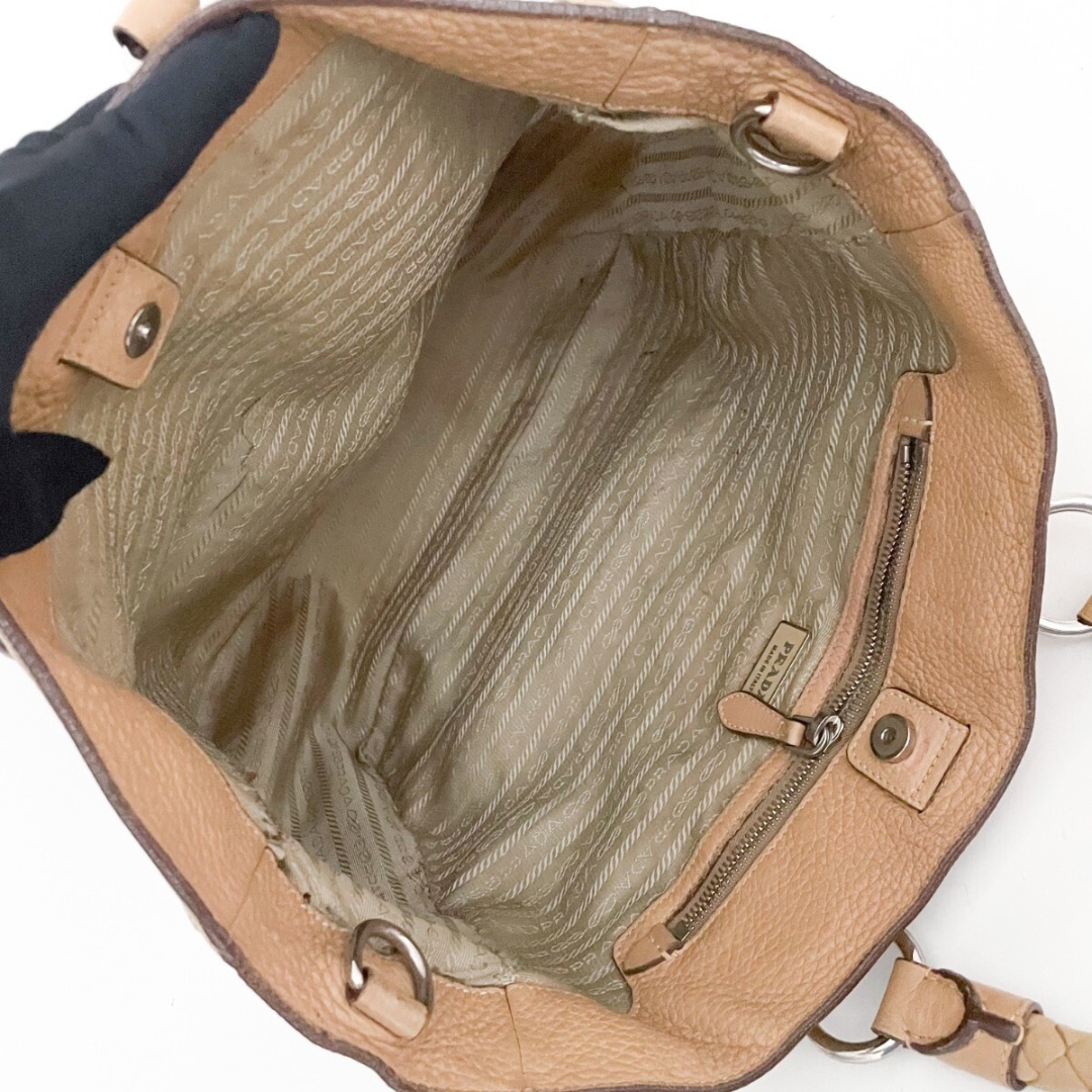 Indvendigt view af beige tekstilfor i Prada tote med lynlåsrum og logo.