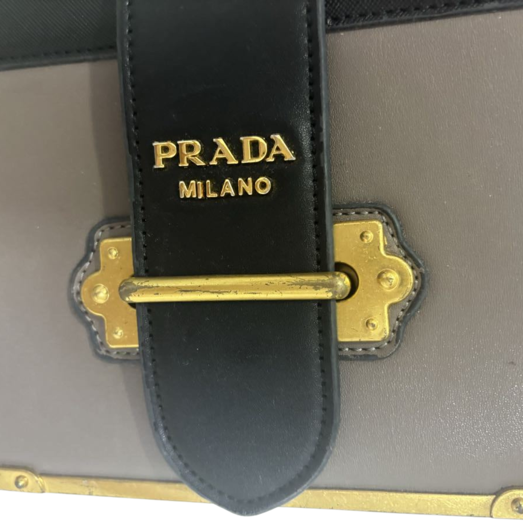 Nærbillede af Prada logo og gulddetaljer på Cahier crossbody taske i sort og grå.