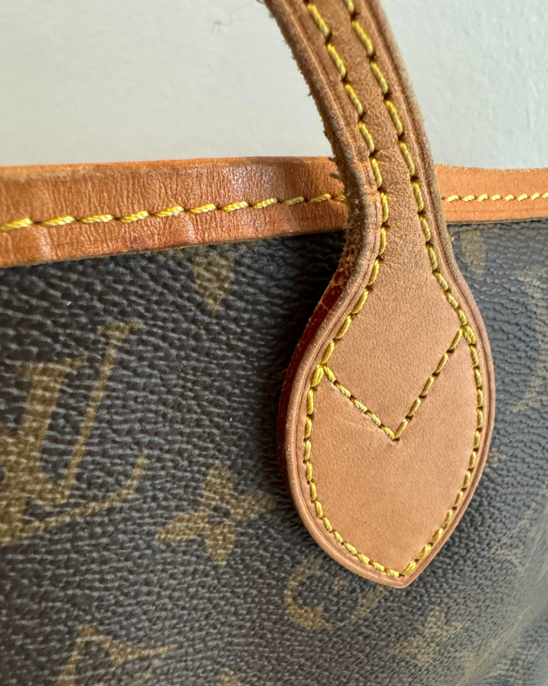 Close-up af håndtag og monogram canvas på Louis Vuitton Neverfull MM