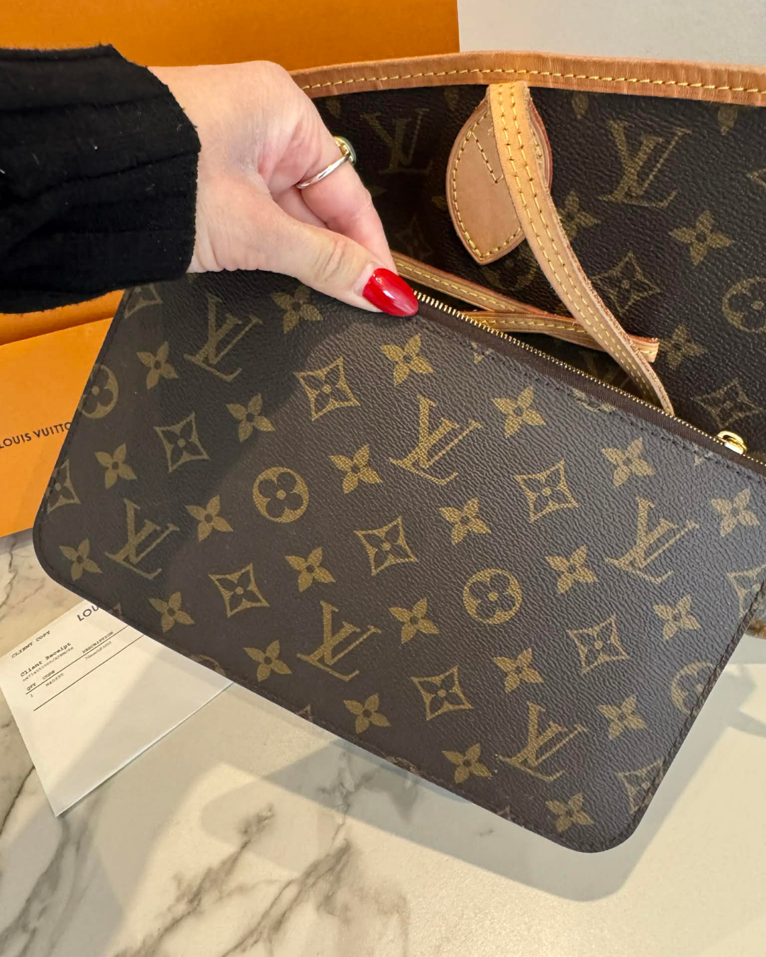 Louis Vuitton Neverfull MM monogram canvas set with pouch held by hand.
