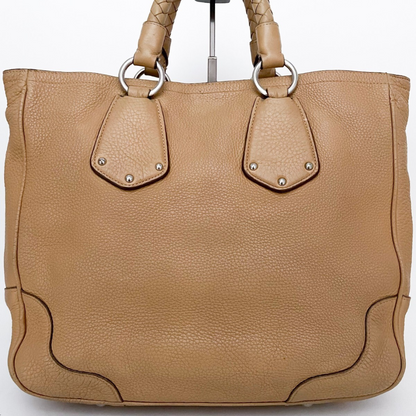 Bagside af Prada tote – struktureret beige læder og sølv hardware tæt på.